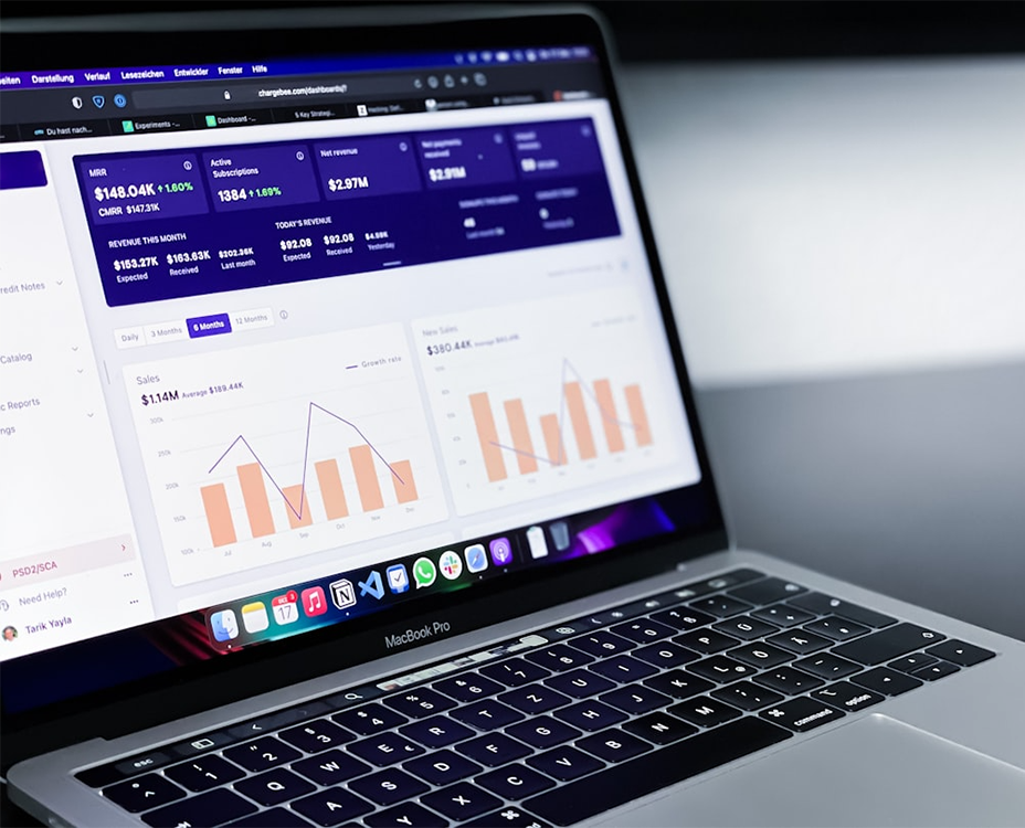 A laptop displays analytics on its screen, featuring graphs and financial data in purple and orange tones.